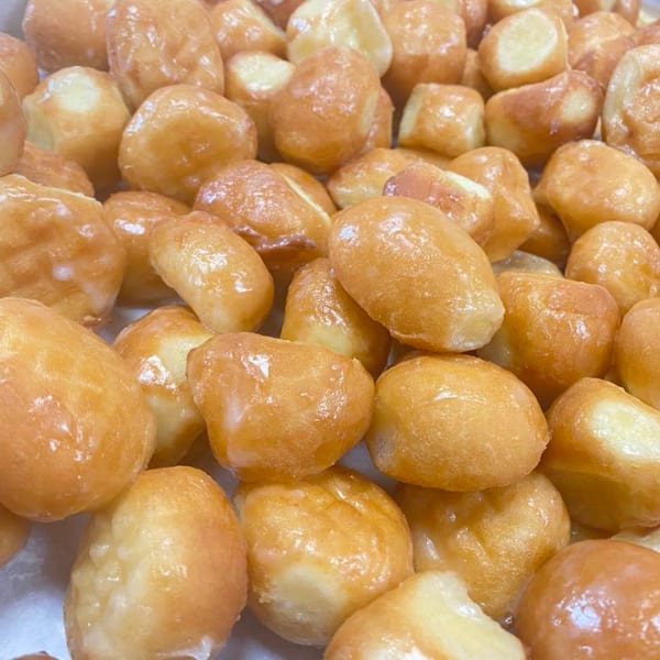 Close-up of numerous golden-brown glazed donut holes.