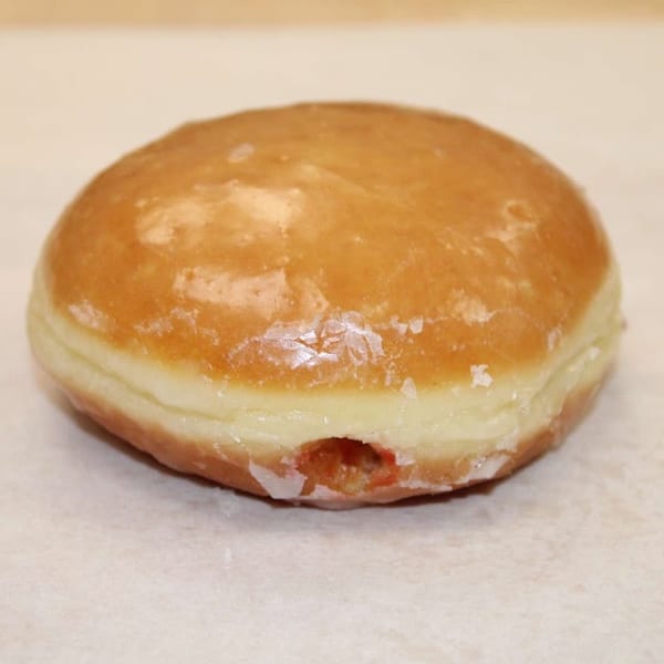 Glazed jelly-filled donut with a small peek of red filling.